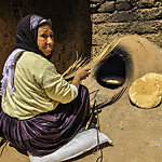 Moroccan woman baking bread (khubz) in a clay oven.