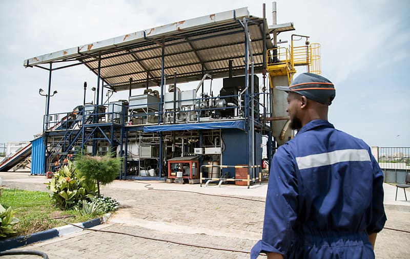 Janicki Omni Processor waste treatment plant in Dakar with worker in blue overalls standing in the foreground.