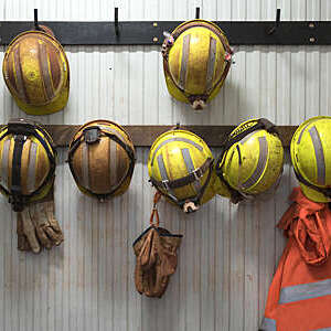 Safety helmets and gloves hang from a rack on a mining site